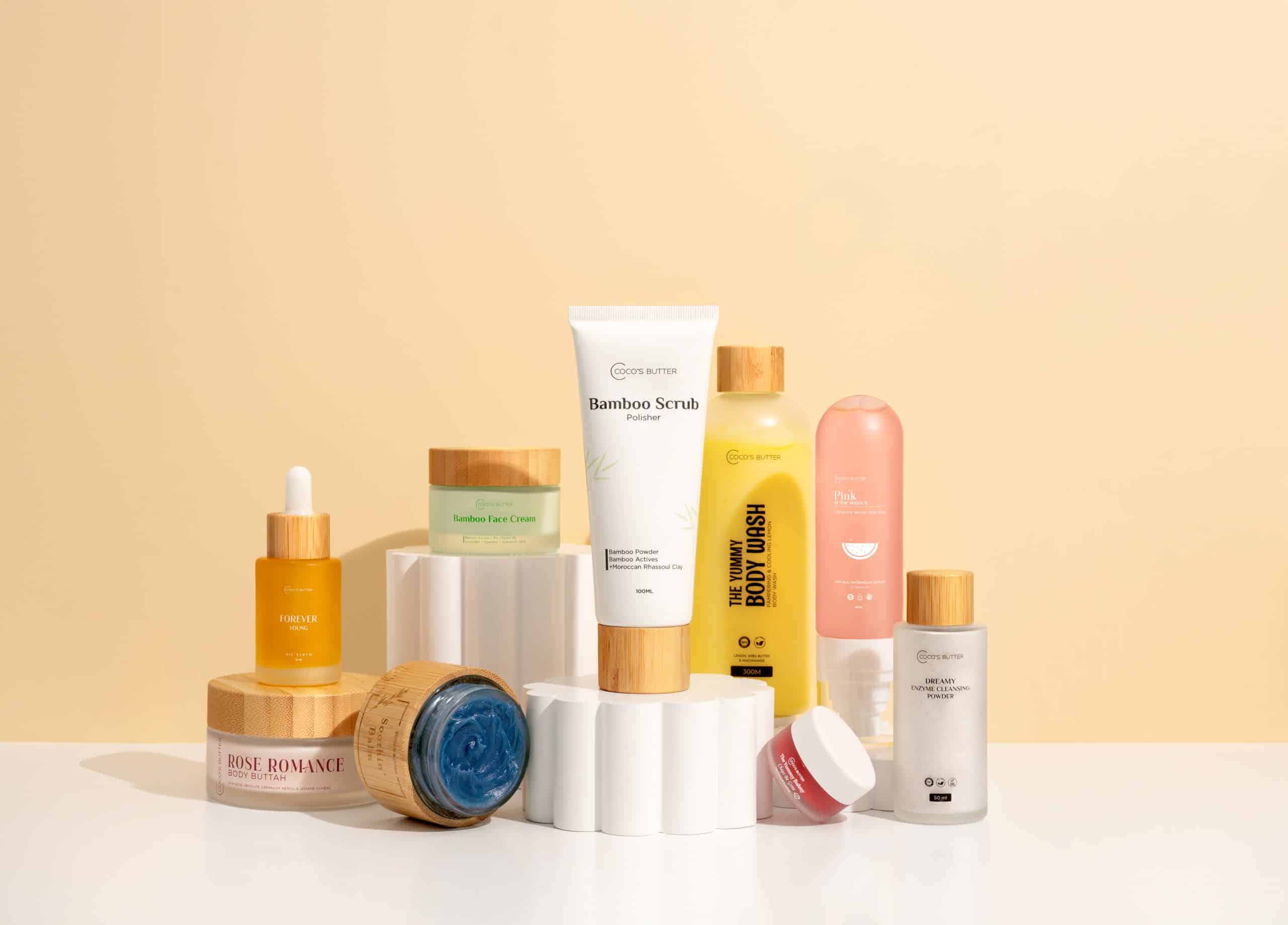 Coco’s Butter skincare formulas arranged on white display stands against a warm beige backdrop
